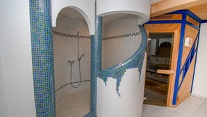 Un baño con ducha, paredes de azulejos y puerta de madera.