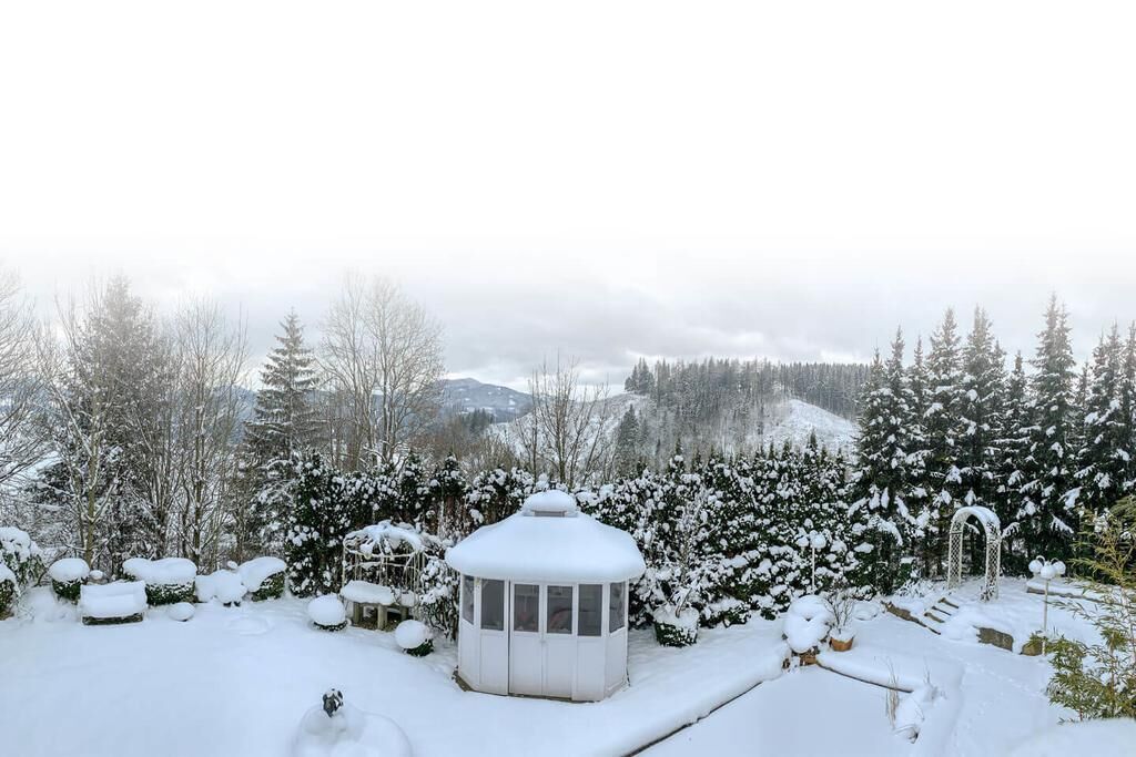 A snow-covered garden with a gazebo and snow-covered trees.