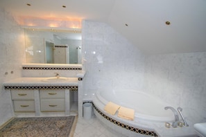 A modern bathroom with a large bathtub, a sink with a mirror above it, and a patterned floor. - Villa Salza (Mitterberg-Sankt Martin)