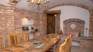 Un comedor rústico con pared de ladrillo, sillas de madera, una mesa larga de madera y una chimenea de ladrillo.