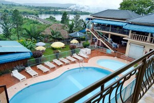 Un hotel con piscina, zona de estar al aire libre y vistas a un río.