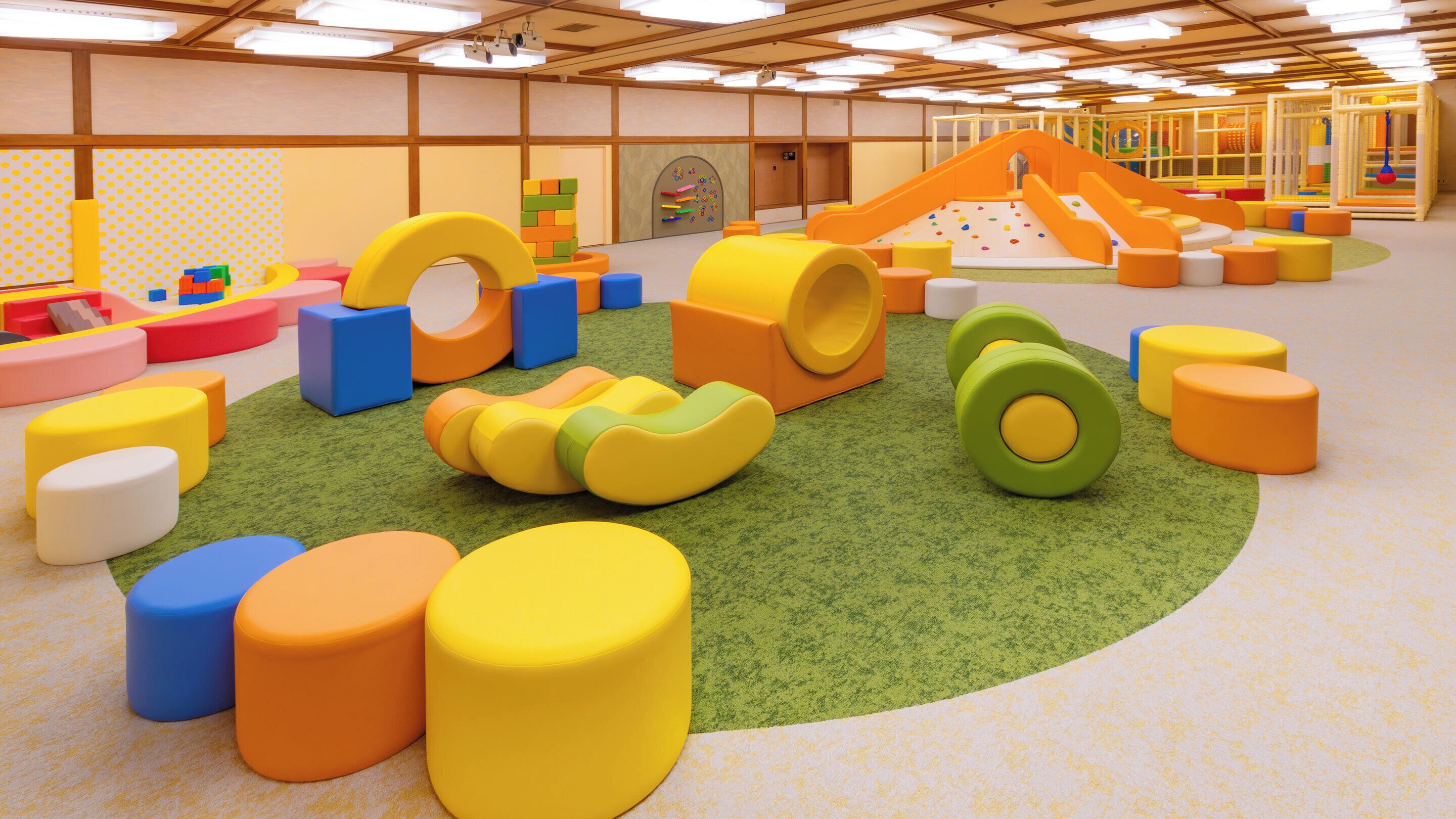 Zona de juegos con estructuras blandas de colores y un tobogán.