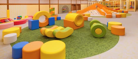 Zona de juegos con estructuras blandas de colores y un tobogán.