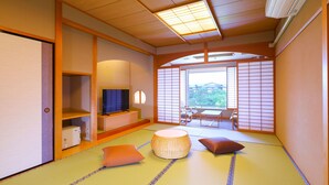 A traditional Japanese room with tatami flooring, a television, a low table, and a view of a garden through a shoji screen. - Ooedo Onsen Monogatari Premium Hotel Sokan (Matsushima)