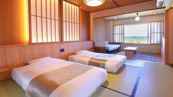 Quarto de hotel com duas camas, uma mesinha e vista para o mar.