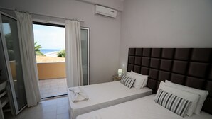 A hotel room with two beds, a view of the beach, and an air conditioning unit on the wall. - Scheria Hotel (Corfu)