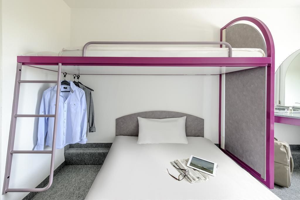 Een stapelbed met een ladder, een klein bureau en een spiegel.