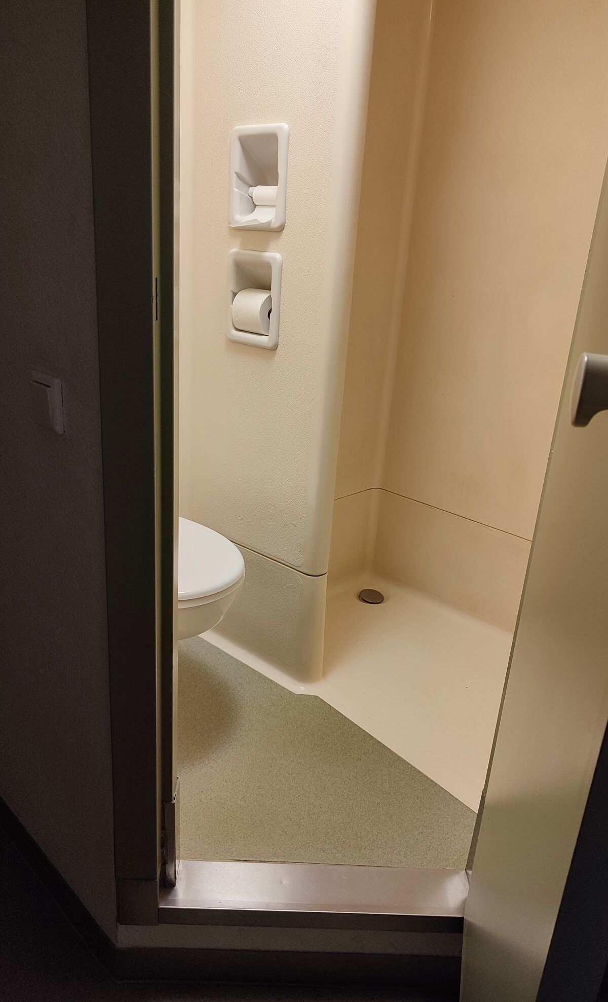 Een kleine, afgesloten douchecel met een toilet en een wastafel.