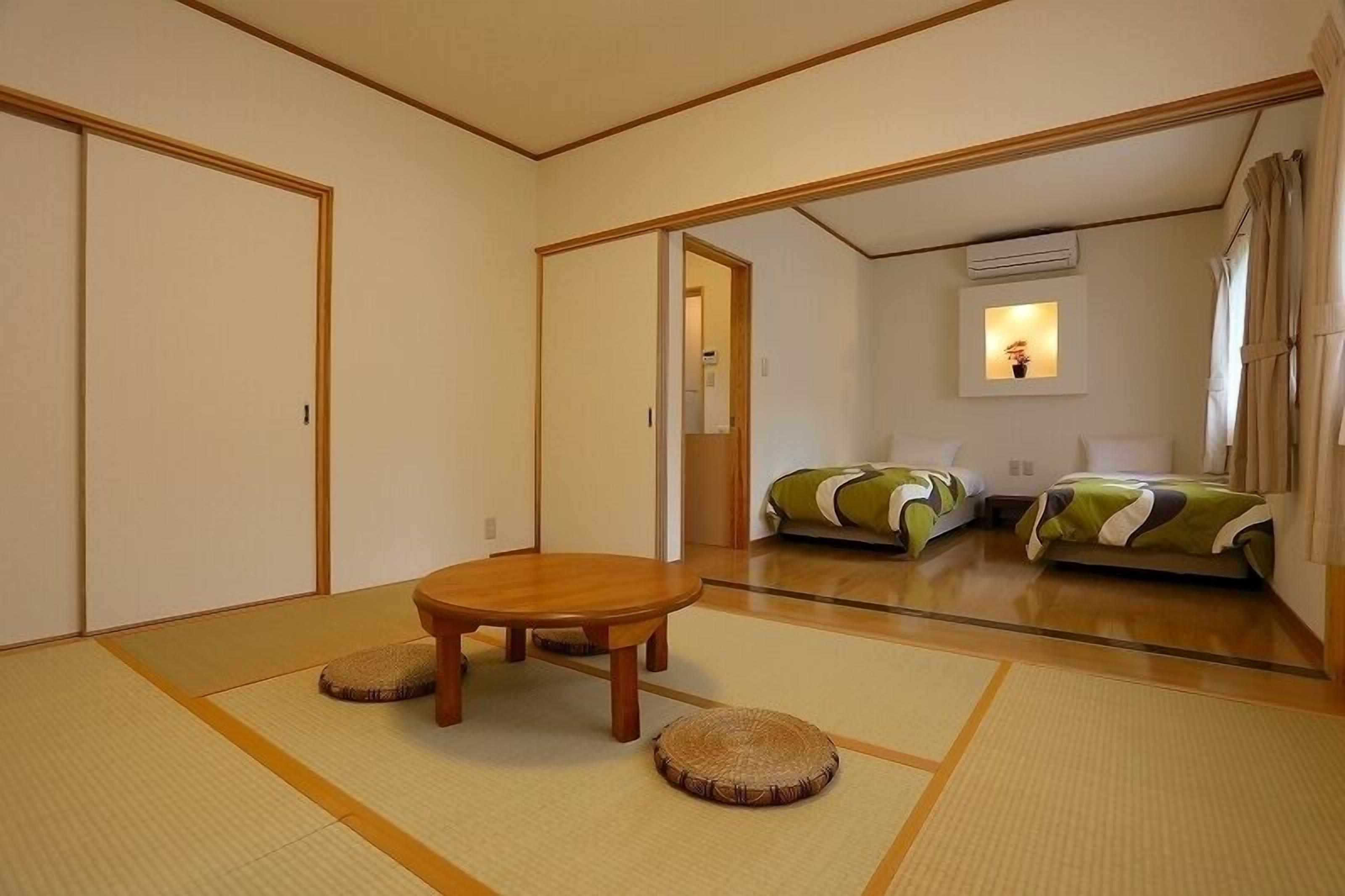 A traditional Japanese room with tatami flooring, a wooden table, and two futons.