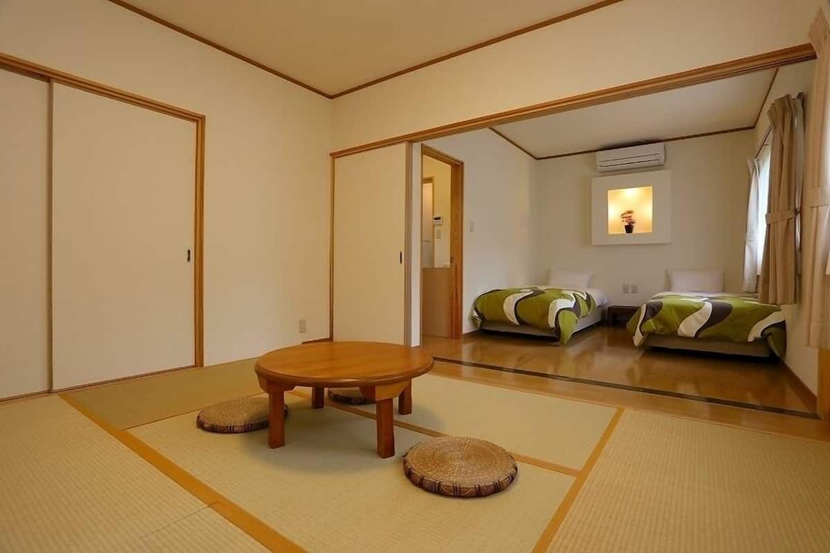 Ein traditioneller japanischer Raum mit Tatami-Boden, einem Holztisch und zwei Futonbetten.