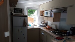 A compact kitchen with a refrigerator, microwave, stove, and sink.