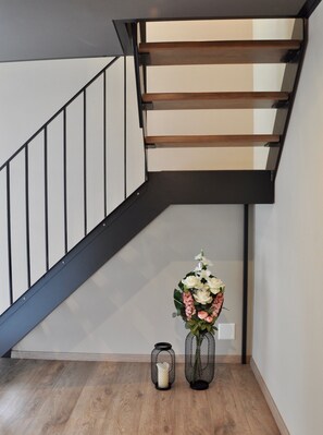 Uma escadaria com design moderno, corrimão de madeira e guarda-corpo de metal.