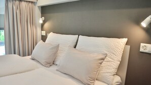 A neatly made bed with white linens and pillows, a grey headboard, and a bedside lamp. - The Loft Interlaken (Interlaken)