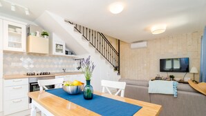 A modern kitchen with white cabinets, a wooden dining table, and a staircase. - Villa Sofija - Three Bedroom Villa with Terrace and Swimming Pool (Zaton Doli)