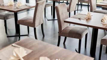 Een restaurant interieur met meerdere tafels en stoelen, elk gedekt met een servet, lepel en vork.