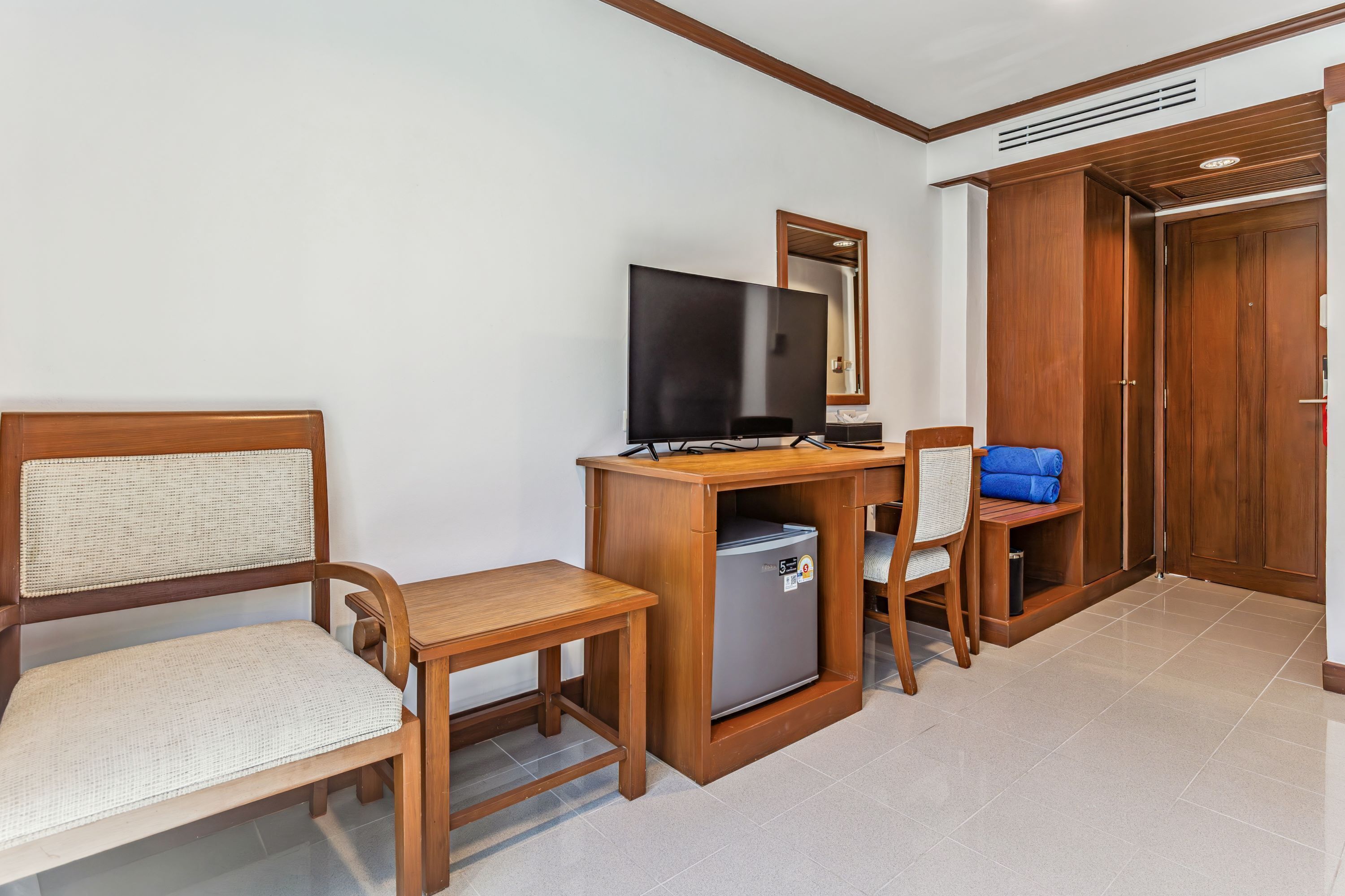 Ein Hotelzimmer mit einem Holztisch, einem Fernseher, einer kleinen Kühlbox und einem Kleiderschrank.