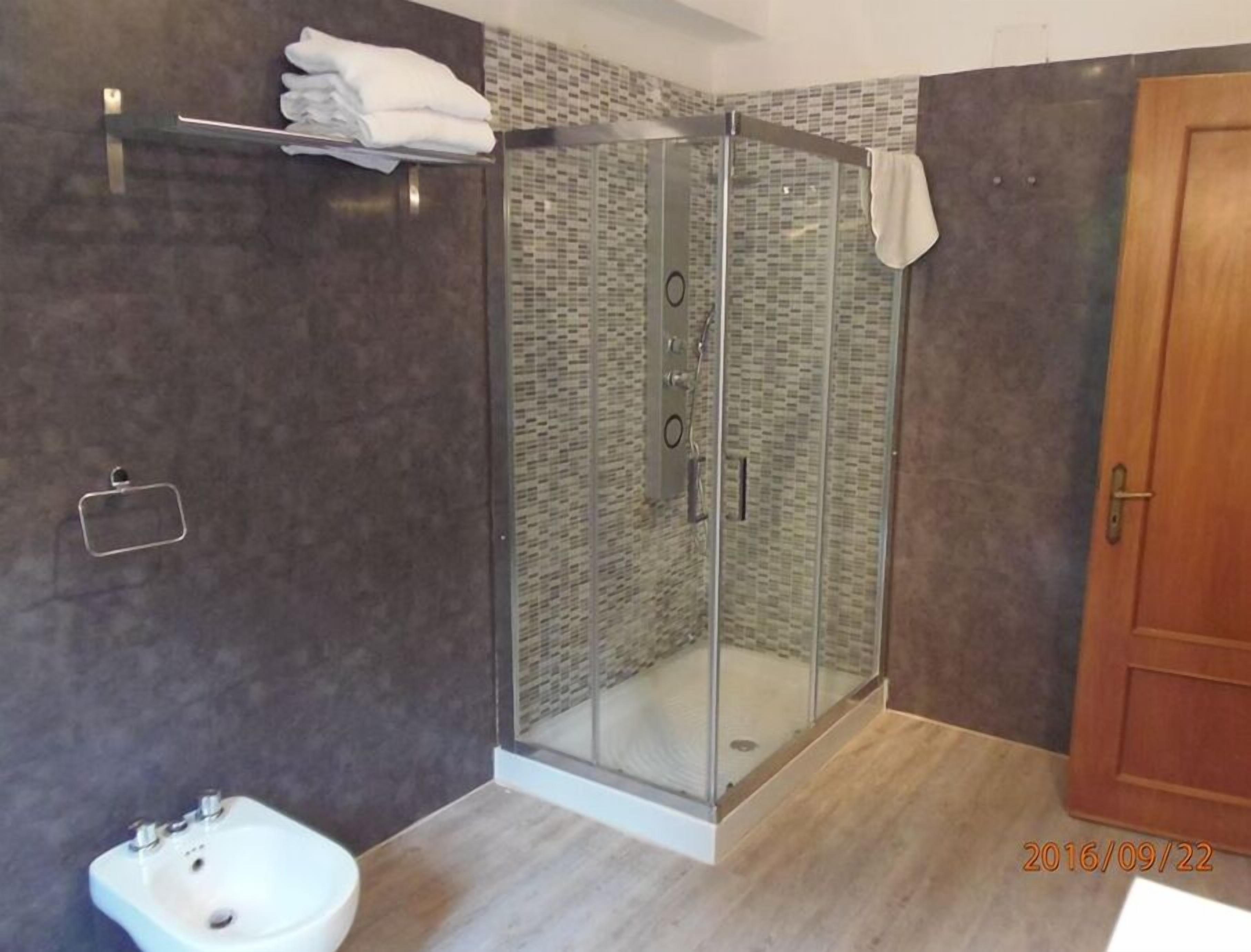 Eenvoudige tweepersoonskamer | Badkamer | Een douche, een haardroger, een bidet, handdoeken