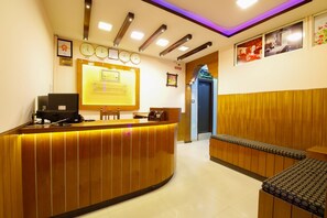 A reception desk with a computer, a clock, and a framed certificate on the wall. - Lusia Inn (Bengaluru)