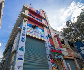 A multi-story building with a prominent sign for 'Lusia Inn Lodge' and various advertisements for construction materials. - Lusia Inn (Bengaluru)