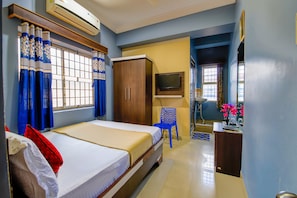 Una camera da letto con un letto, un armadio, una televisione e una scrivania con una sedia.