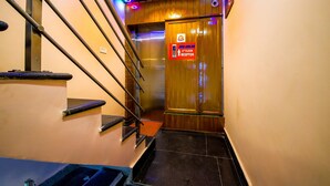 A staircase leading to an elevator with a sign indicating the 2nd floor reception. - Lusia Inn (Bengaluru)