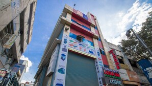 A multi-story building with a closed shutter on the ground floor, signs for a labor shed, cold storage panel, and a lodge. - Lusia Inn (Bengaluru)