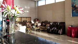 A spacious living room with a large sofa, a coffee table, and a red table. There is a vase with flowers on the coffee table and a chandelier on the ceiling. - Oriental Beauty Hotel (Guangzhou)