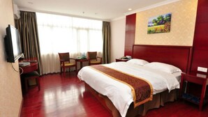 A hotel room with a large bed, a desk with a chair, a television, and a painting on the wall. - Oriental Beauty Hotel (Guangzhou)