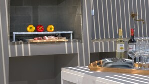 Un barbecue avec des légumes et de la viande, une bouteille de vin et des verres sur une table.