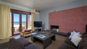 Un salon doté d’une télévision, d’une cheminée et offrant une vue sur la plage.