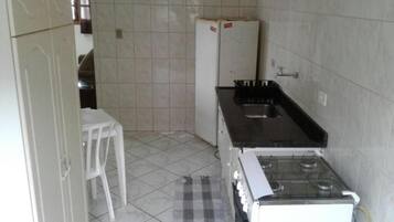 Una cocina pequeña con estufa a gas, pileta y refrigerador.