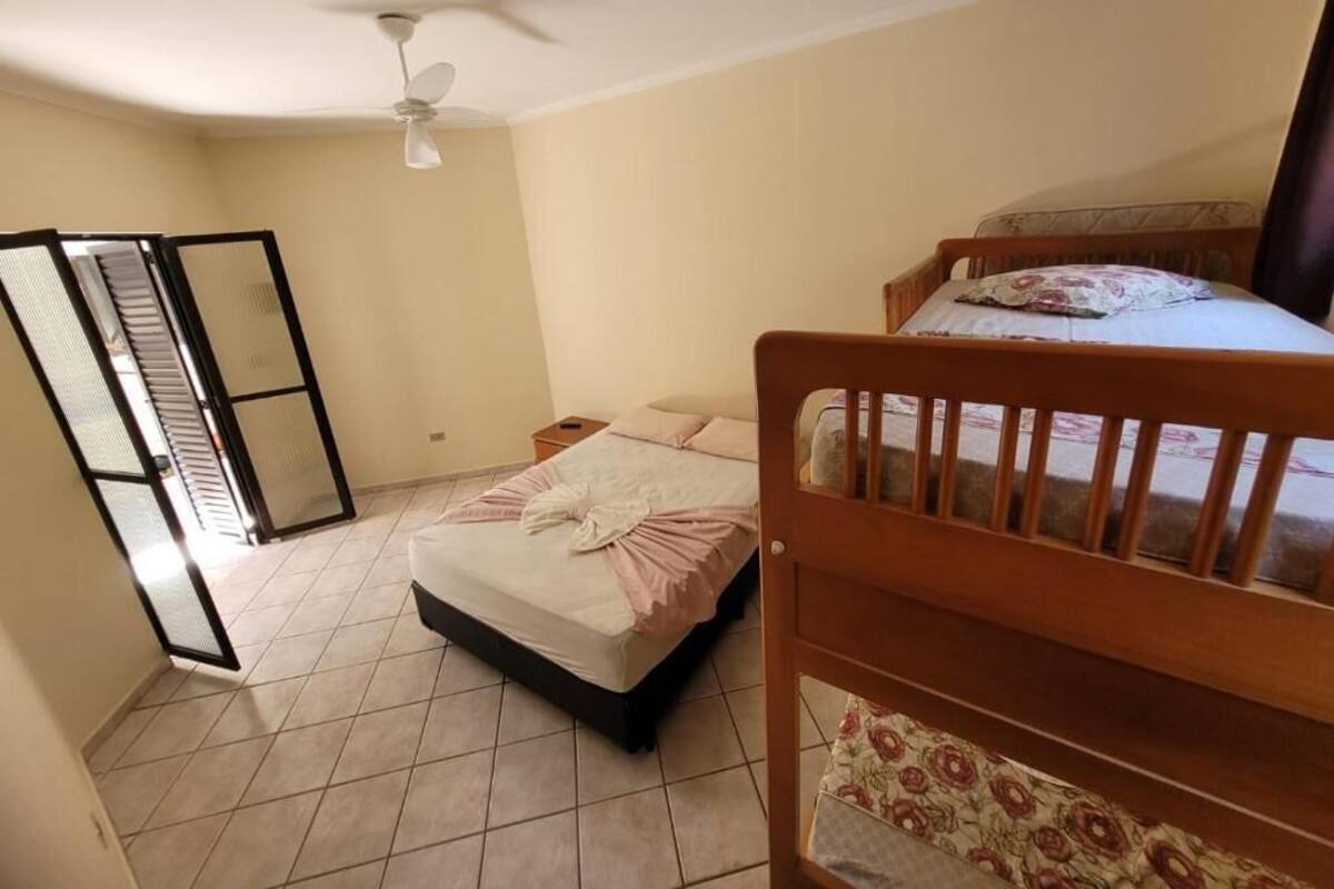 A bedroom with a bed, a ceiling fan, and a window.