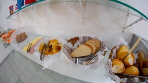 A buffet with various food items including bread, pastries, and fruits. - Pousada D'Ibiza (Itanhaém)