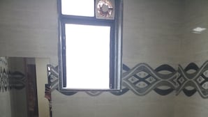 A bathroom with a sink, toilet, and a window. - Hotel Shahi Darbar (Navsari)