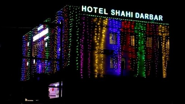 A building with the sign "HOTEL SHAHI DARBAR" illuminated with colorful lights. - Hotel Shahi Darbar (Navsari)