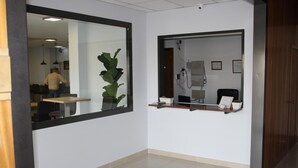 Een receptiezone met een receptiebalie, een grote spiegel en een kamerplant.