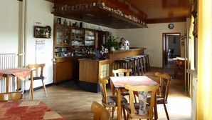 Een sfeervol restaurant met houten meubels, een bar en een open keuken.