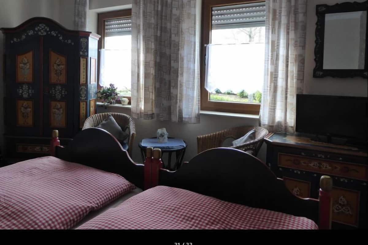 Una habitación con dos camas, un aparador, una silla, una mesita y un televisor.