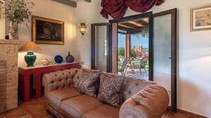 A living room with a sofa, decorative pillows, a vase, and a painting on the wall. - La Casa del Torero (Vejer de la Frontera)