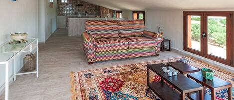 A spacious living area with a colorful sofa, a wooden coffee table, and a large patterned rug.
