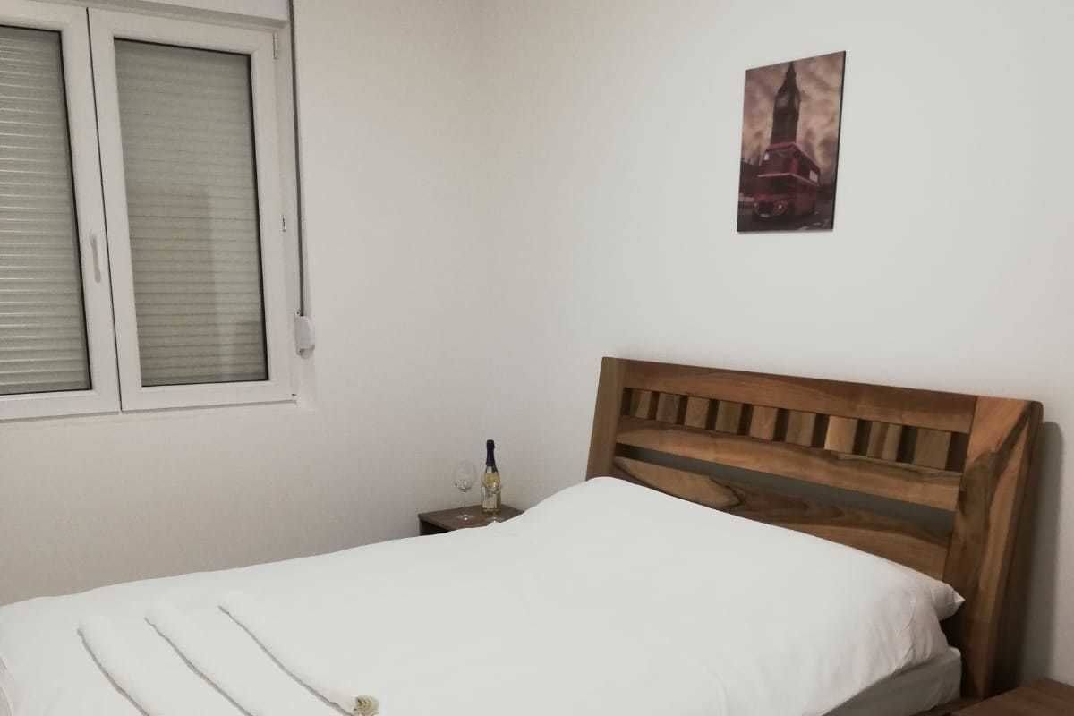 A single bed with a wooden headboard in a room with white walls.