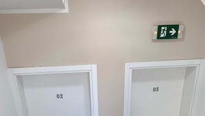 A hallway with two doors labeled 02 and 03, a potted plant, and a red mat at the bottom of the stairs. - Airport View Apartments (Belgrade)