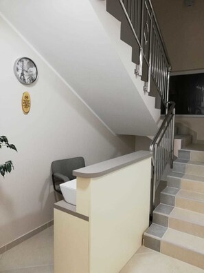 A reception desk with a staircase leading to an upper floor.