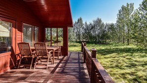 Een houten terras met buitenmeubilair en uitzicht op een bos.