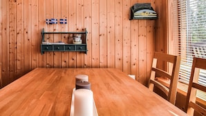 Een houten eettafel met kaarsen, een plank met vlaggen en een raam met zonwering.