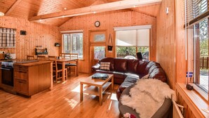 Een gezellig interieur van een chalet, met een houten eethoek, een bank en een keuken met een spoelbak en kastjes.