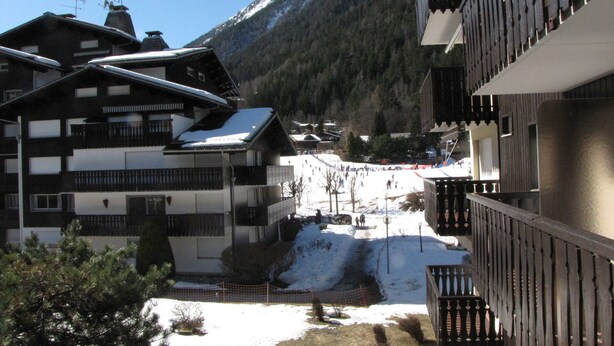 Une station de ski comprenant plusieurs bâtiments, dont un hôtel doté de balcons et offrant une vue sur les montagnes.