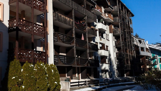A multi-story building with balconies, a central tower, and a snow-covered ground. - Studio Chamonix 20m², 4 pers, balcony, parking (Chamonix-Mont-Blanc)