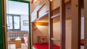 A room with bunk beds, a small table, and a couch. - Studio Chamonix 20m², 4 pers, balcony, parking (Chamonix-Mont-Blanc)