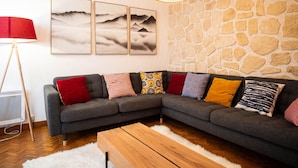 A modern living room with a grey sectional sofa, a wooden coffee table, and a stone wall. - Stunning downtown apartment - Pets allowed, WiFi (Chamonix-Mont-Blanc)